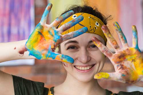 Woman smiling and showing her hands with paint on them